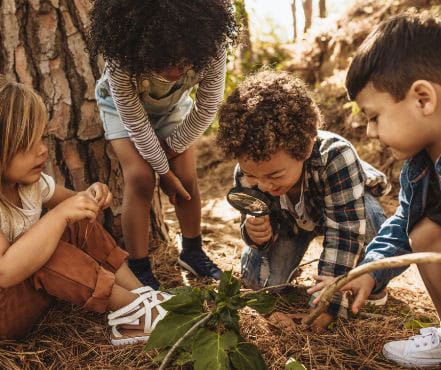 Young people using a magnifying glass to explore their surroundings