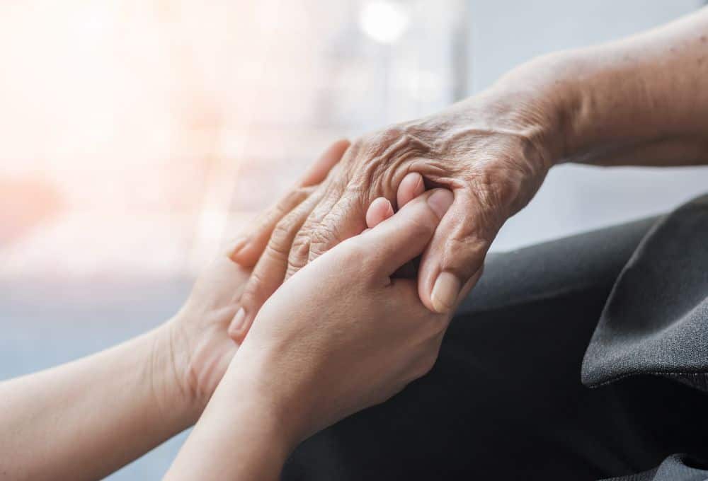 2 hands holding an older person's hand symbolising care and support