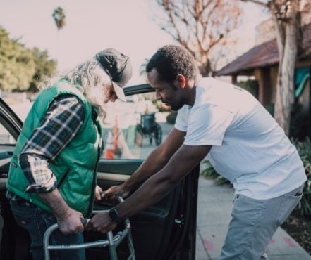 Person helping someone with a walker