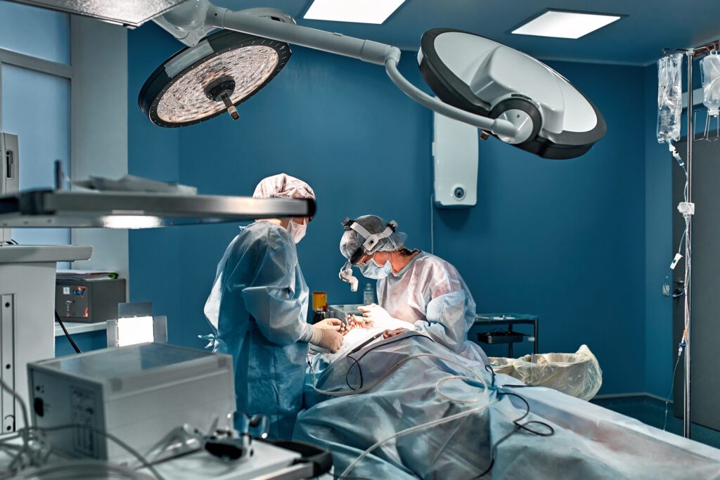Two people are conducting surgery on a patient in a hospital theatre