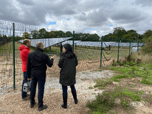 three people looking at fields of solar panels - the PV farm