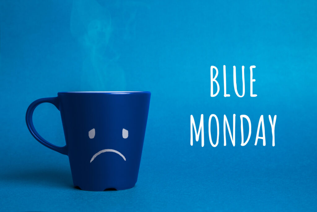 A blue cup with a sad face saying Blue Monday