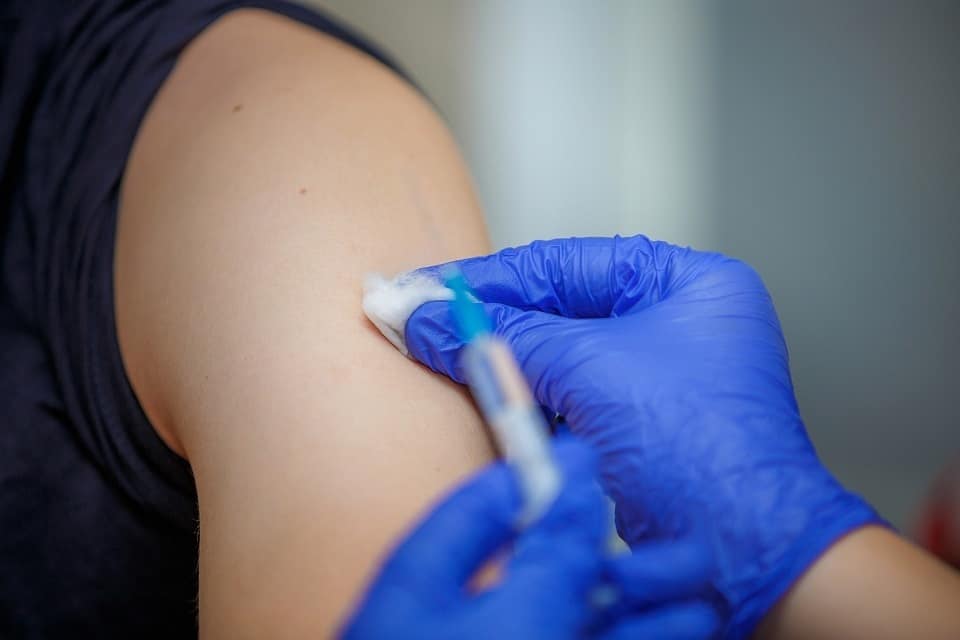 A medical professional cleans an arm before administering a vaccine