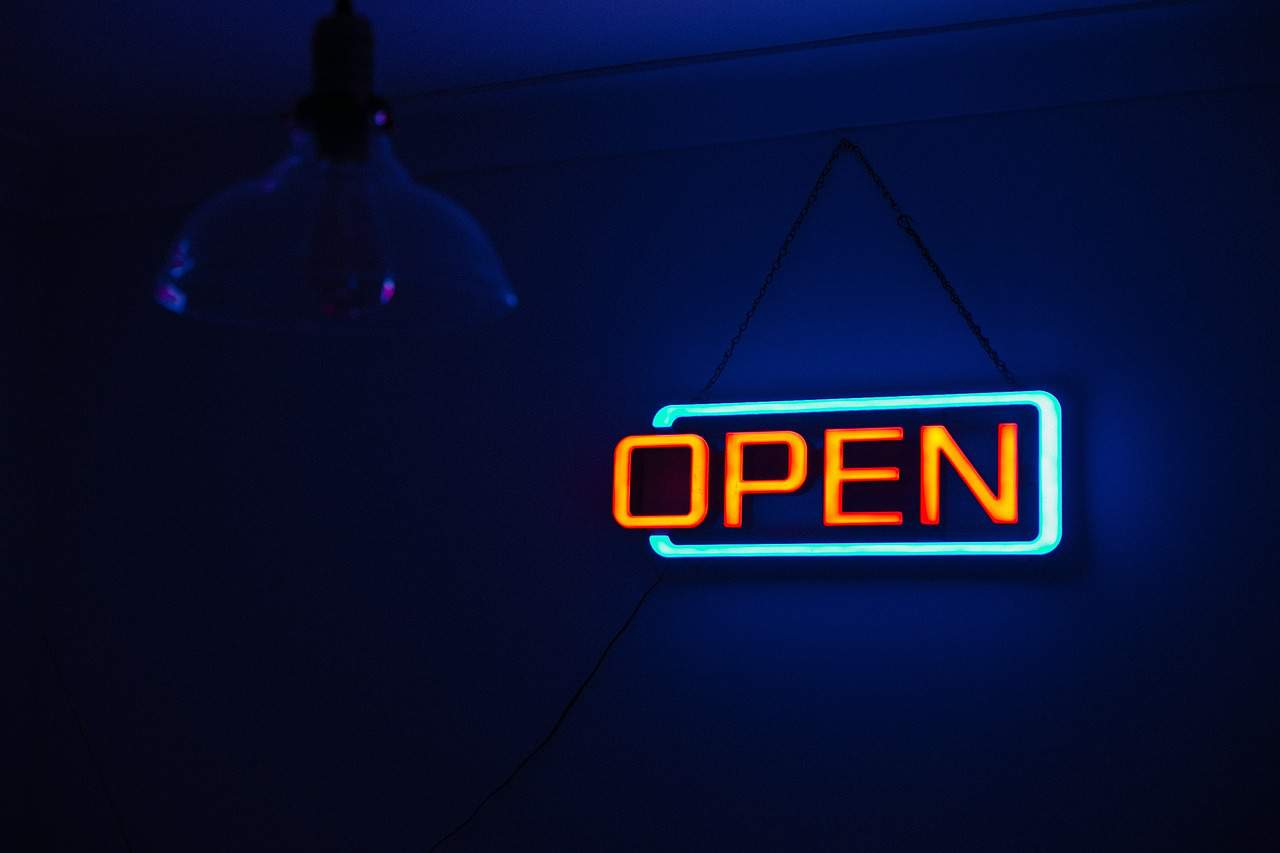 A neon open sign depicting pharmacies are now open to treating a range of common conditions.