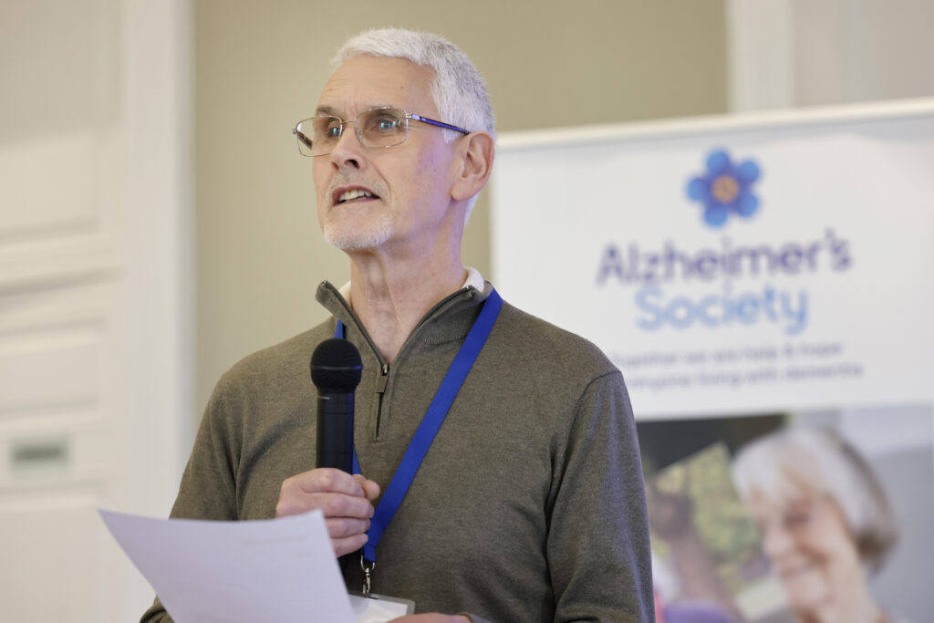 Speaker at the dementia conference with an Alzheimer's Society banner in the background