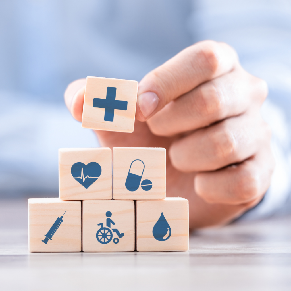 Picture of a hand holding a block to stack on top of other building blocks with health related graphics on the front of them