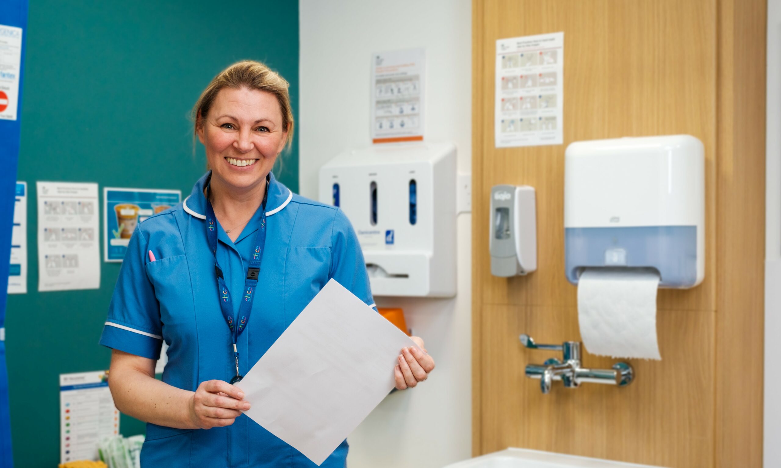 Nurse in a clinical setting holding some papers wearing a blue uniform