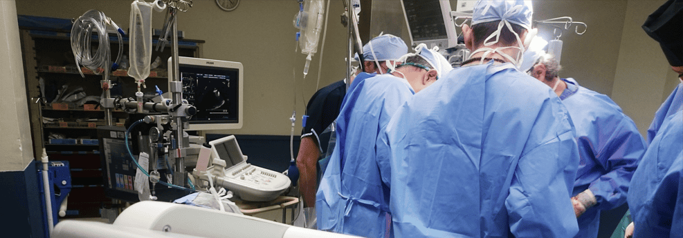 Image of Doctors with back to picture in a hospital theatre surrounded by medical equipment