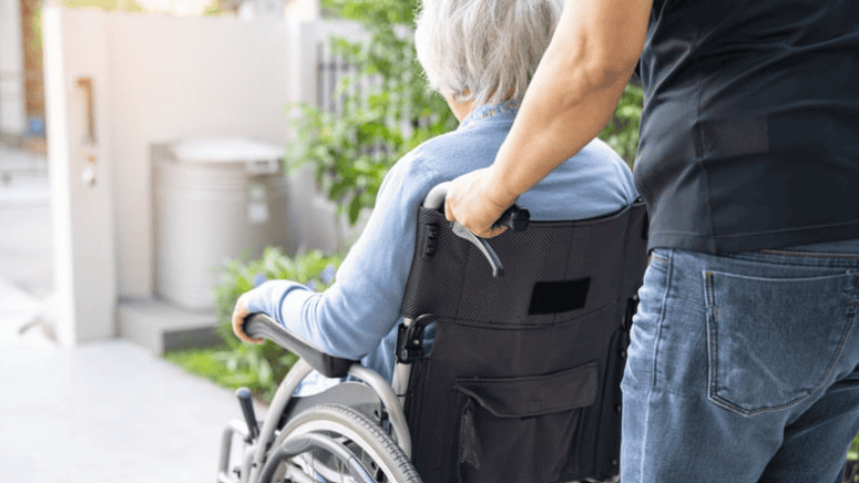 Person pushing a patient in a wheelchair as part of the Voluntary, Community and Social Enterprise sector