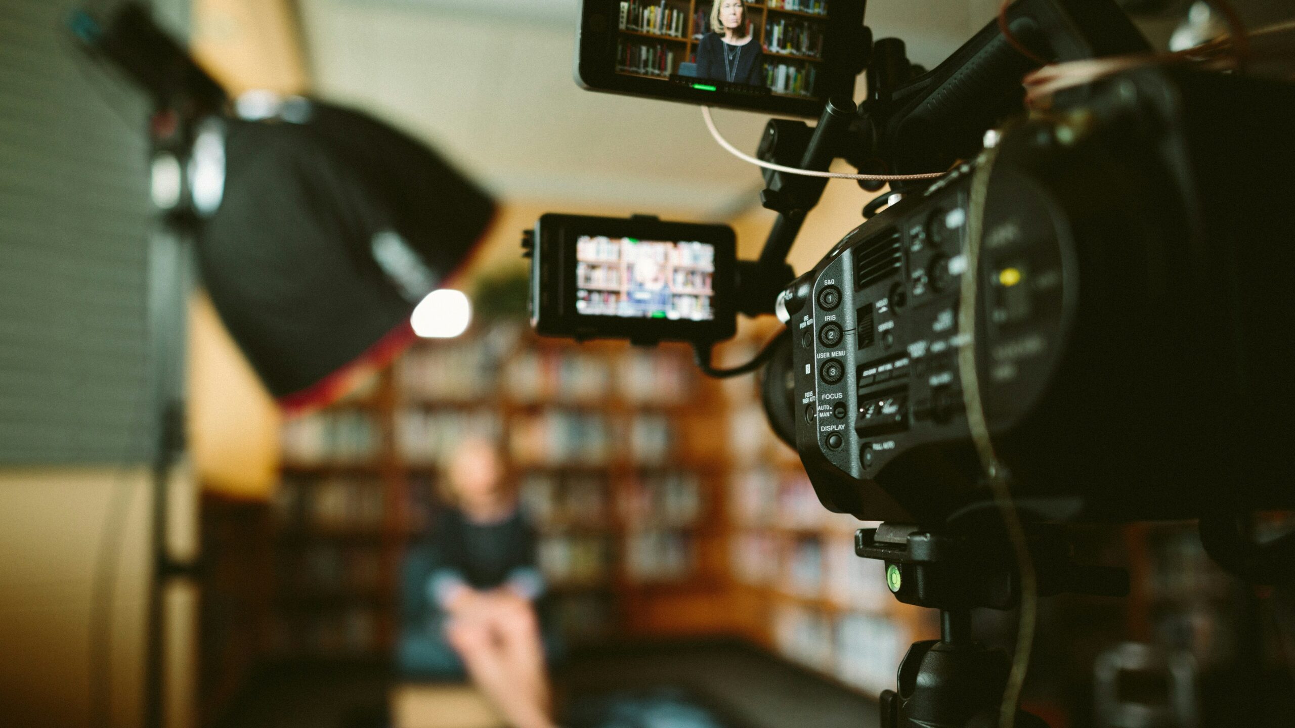 Close up of a film camera capturing content of someone in the foreground blurred out.