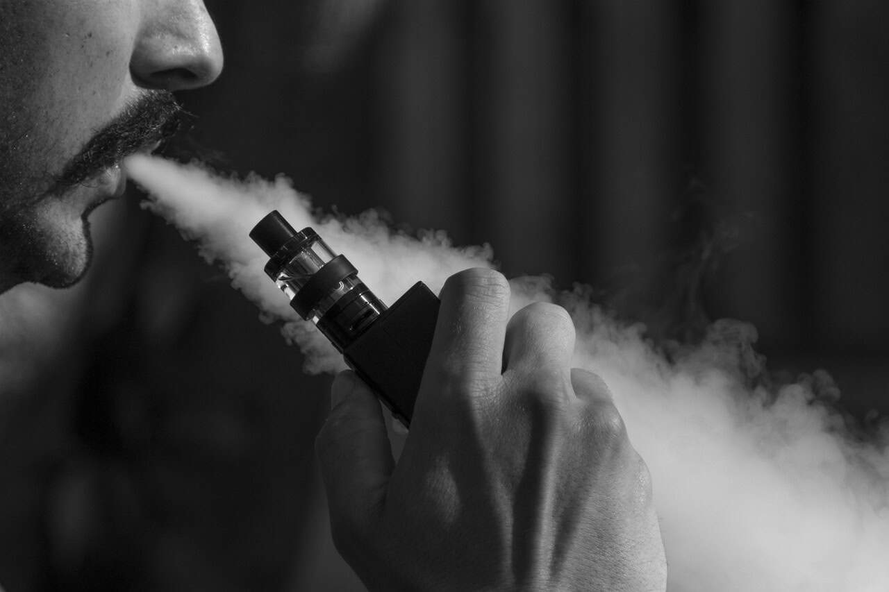 A man blows out vapour from a large e-cigarette