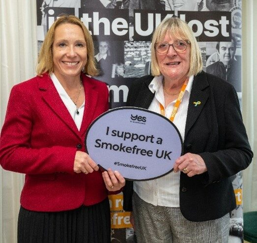 MP Helen Morgan and Hull City Council Councillor Linda Chambers hold up a small sign, saying 'I support a smokefree UK'