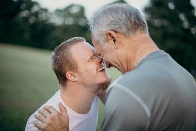 Two men - and older and one younger, possibly father and son - share an embrace